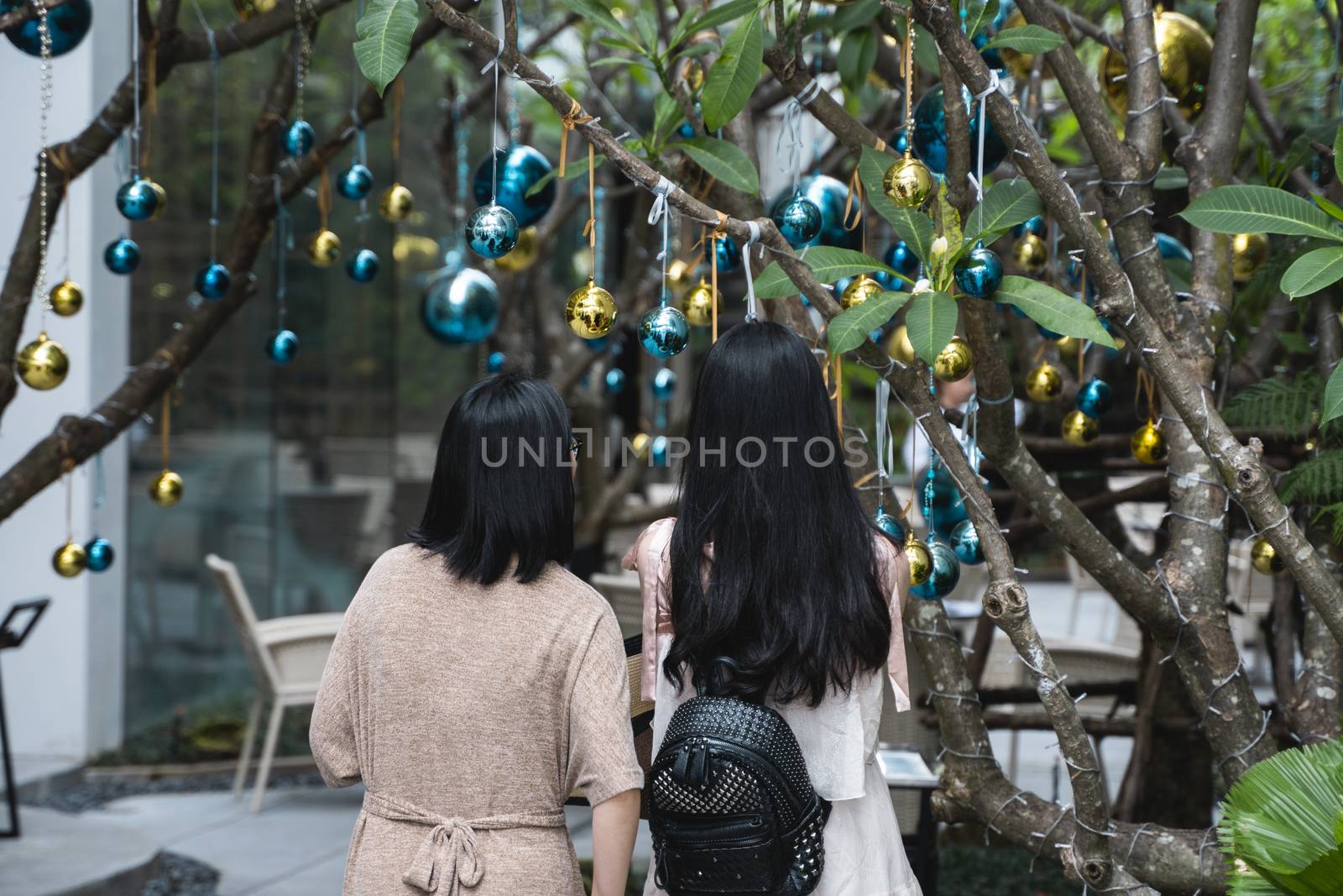 Two girls is standing near decorated Christmas tree with a blue and gold toys and beautiful blue butterfly toy. Holidays. Preparation for New Year and Christmas