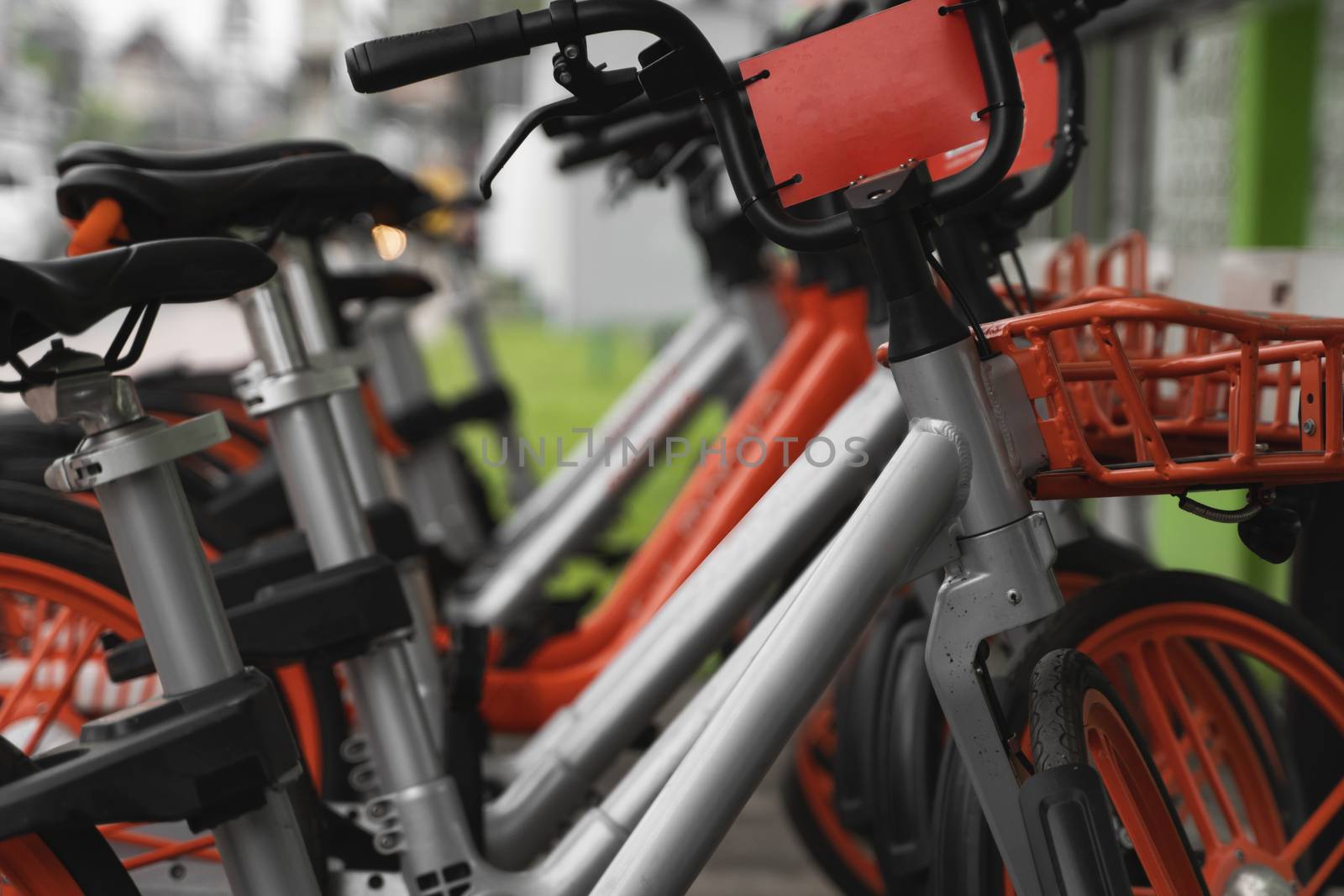 Street transportation orange hybrid rent bicycles with electronic form of payment for traveling around the city stand in row