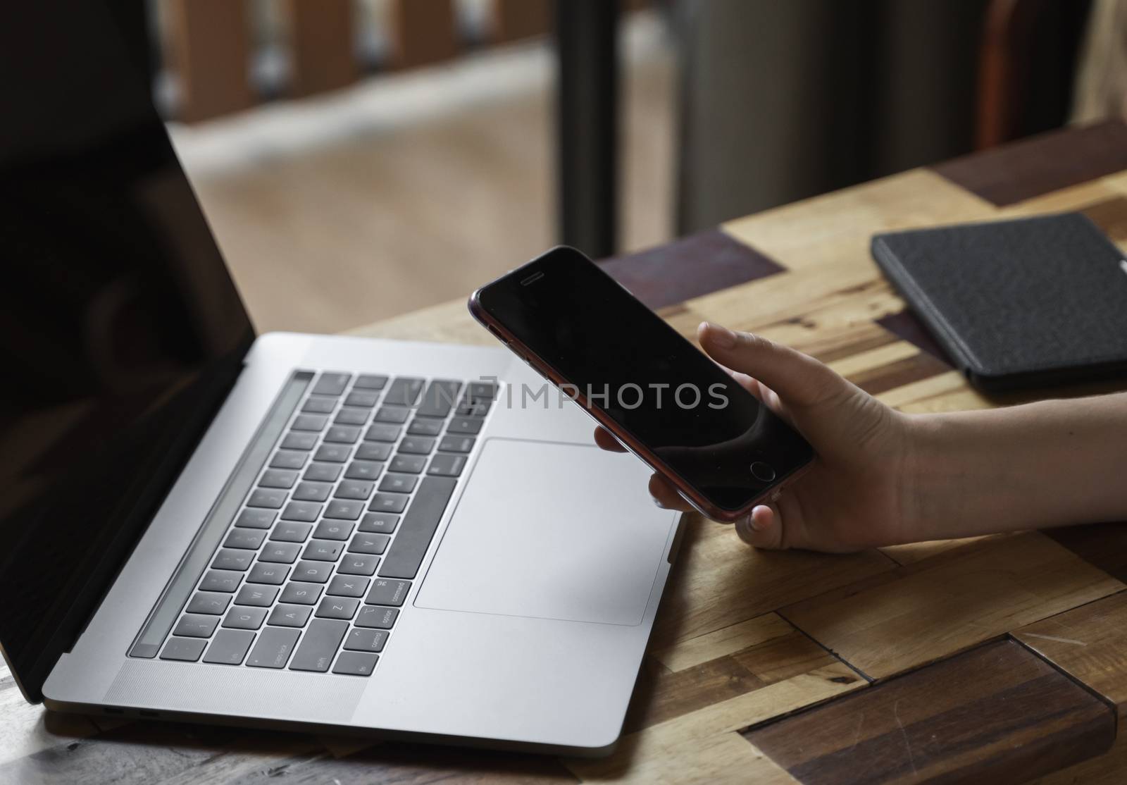 Woman's hands use a smartphone with a laptop. Study and work online, freelance. Self employed or freelance woman, girl working with her laptop sitting at wooden table with a phone and ereader