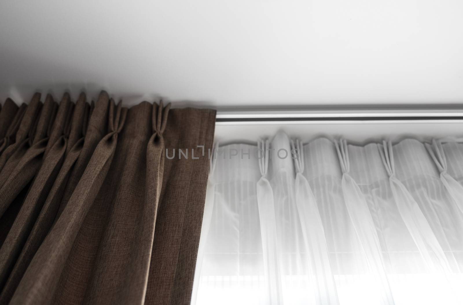 Brown curtains and white tulle on a rail with a white ceiling. Curtain interior decoration in living or sleeping room. Comfortable live in your own home. Sweet confy home