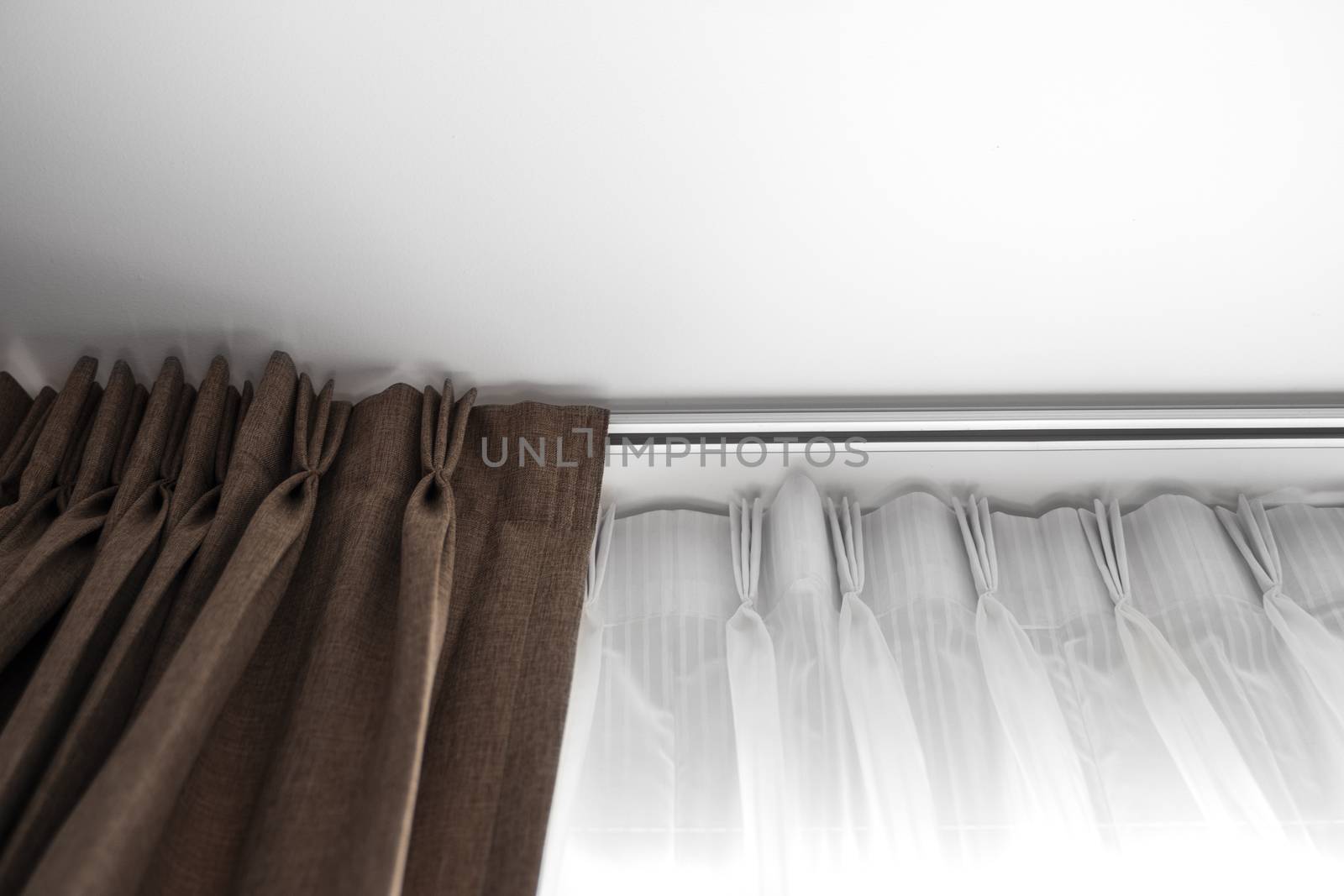 Brown curtains and white tulle on a rail with a white ceiling. Curtain interior decoration in living or sleeping room. Comfortable live in your own home. Sweet confy home
