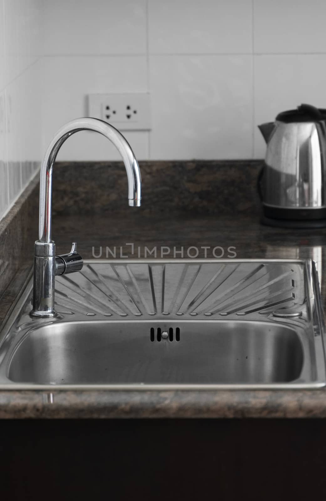 Close up on modern kitchen metal faucet and metal kitchen sink