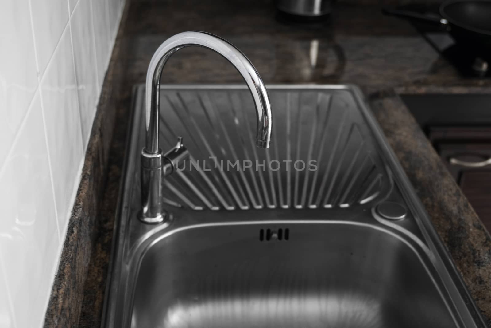 Close up on modern kitchen metal faucet and metal kitchen sink. by vovsht