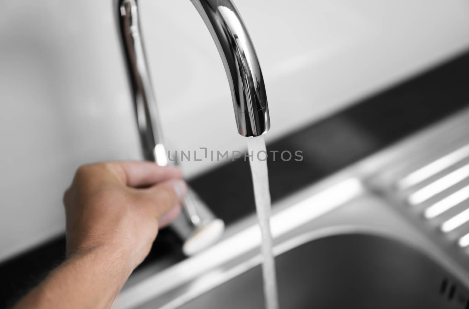 Close up on modern kitchen metal faucet and metal kitchen sink with a running water