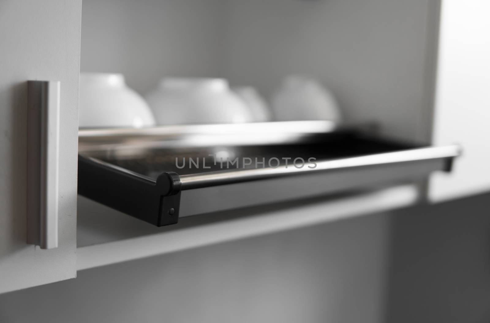 Dish drying metal rack with big nice white clean plates. Traditional comfortable kitchen. Open white dish draining closet with wet dishes of glass and ceramic, plates, bowls drying inside on rack