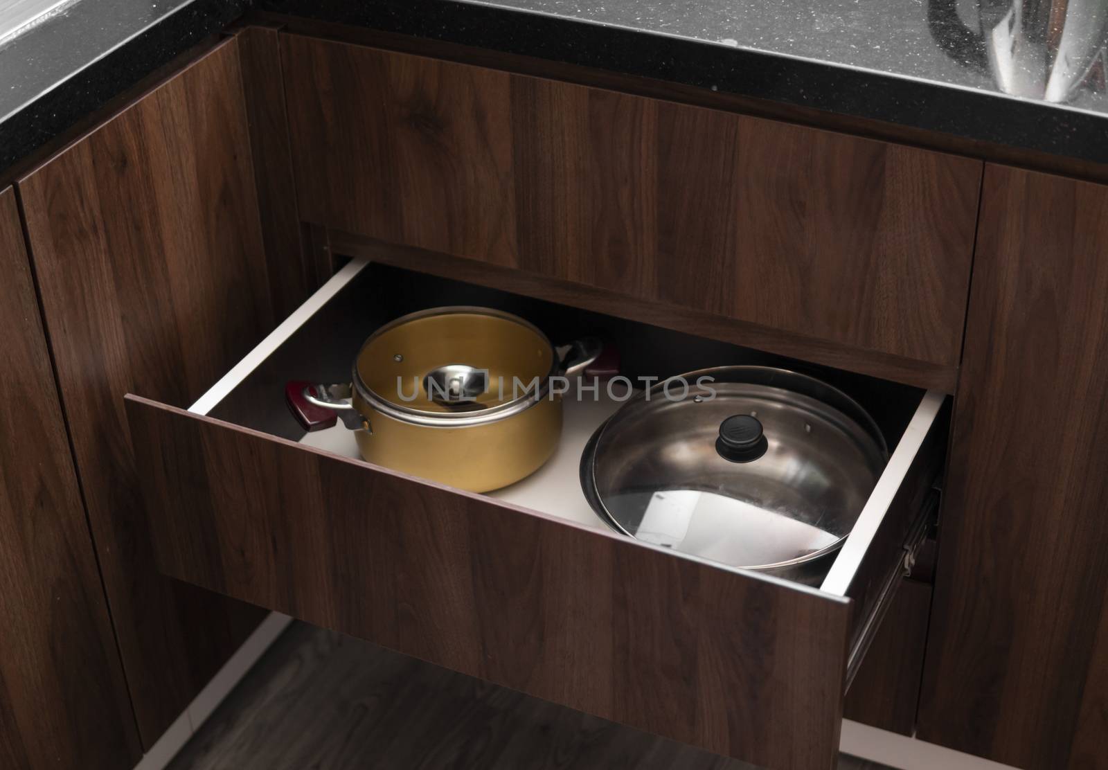 Metal chromed pots in a drawer in a modern kitchen