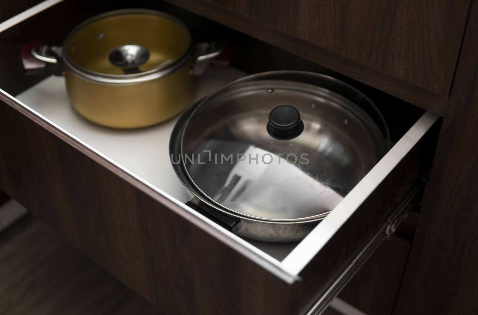 Metal chromed pots in a drawer in a modern kitchen. by vovsht