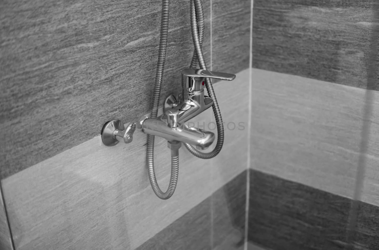 Modern designer tap and shower in bathroom. Closeup of chrome shower, faucet, in the bathroom covered decorative ceramic. Mixer cold hot water. by vovsht