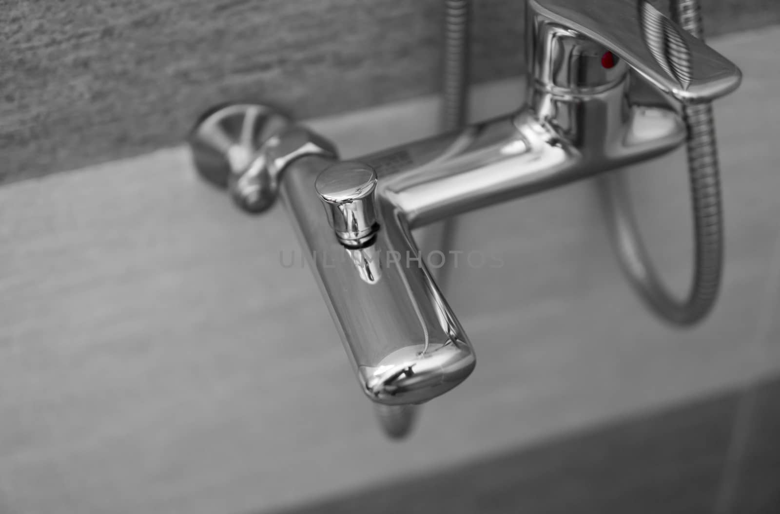 Modern designer tap and shower in bathroom. Closeup of chrome shower, faucet, in the bathroom covered decorative ceramic. Mixer cold hot water. by vovsht