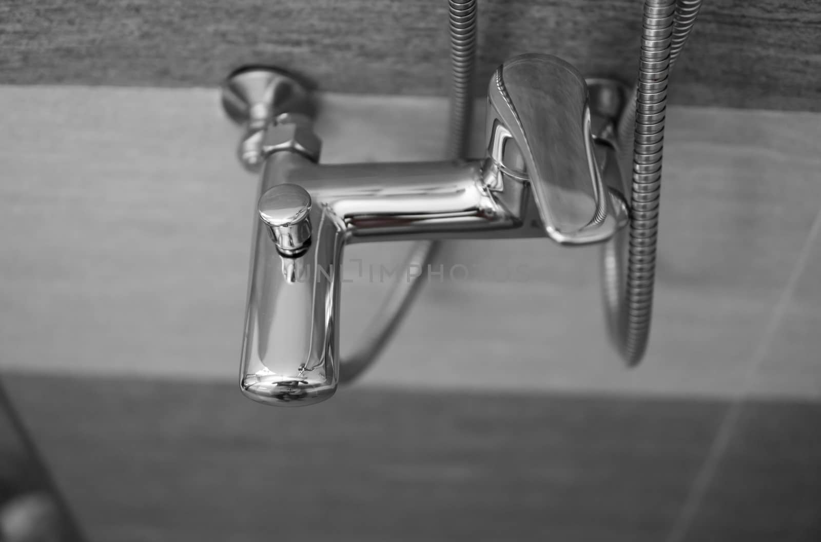 Modern designer tap and shower in bathroom. Closeup of chrome shower, faucet, in the bathroom covered decorative ceramic. Mixer cold hot water. by vovsht