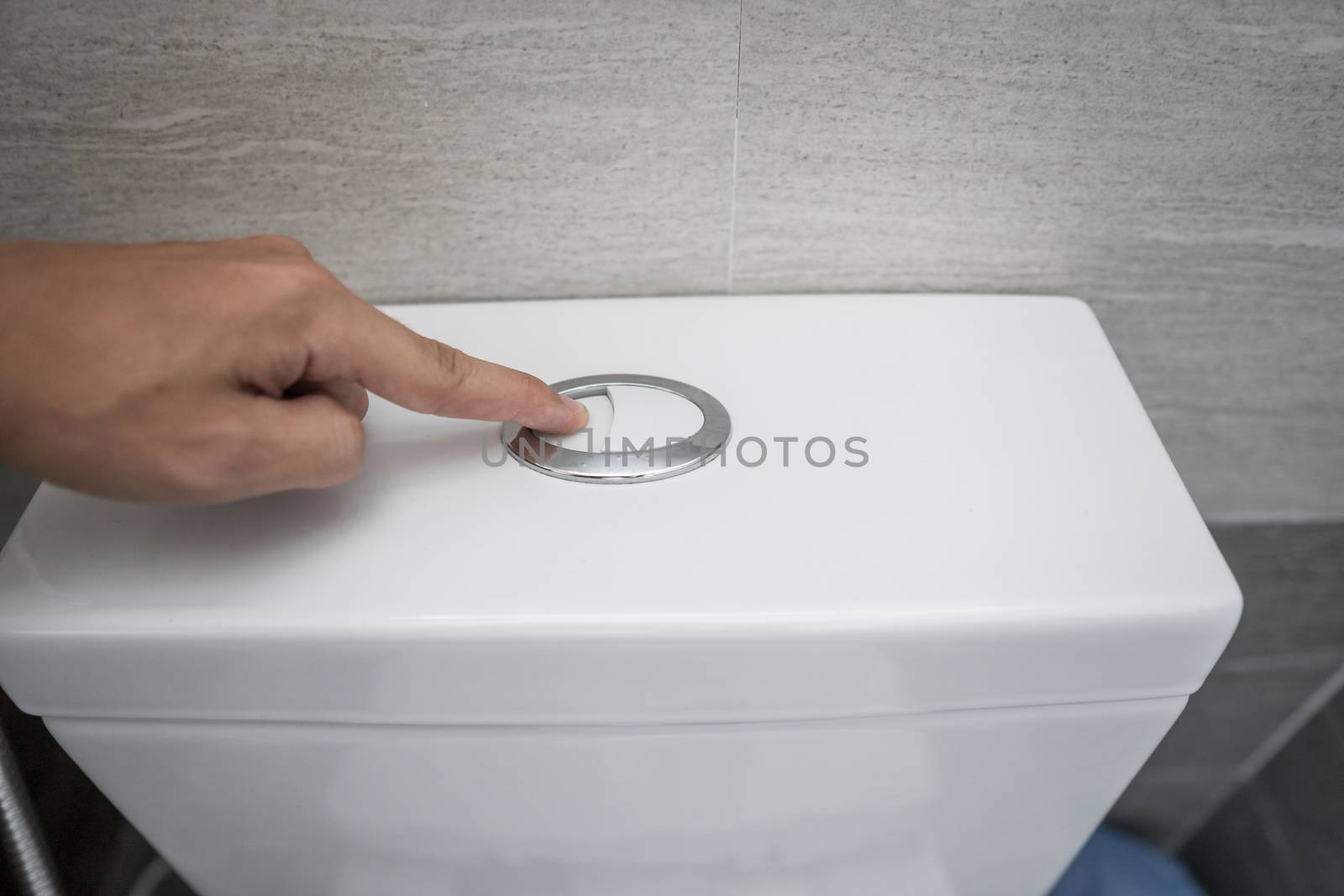 Close up of finger pushing a flush toilet button for cleaning a toilet