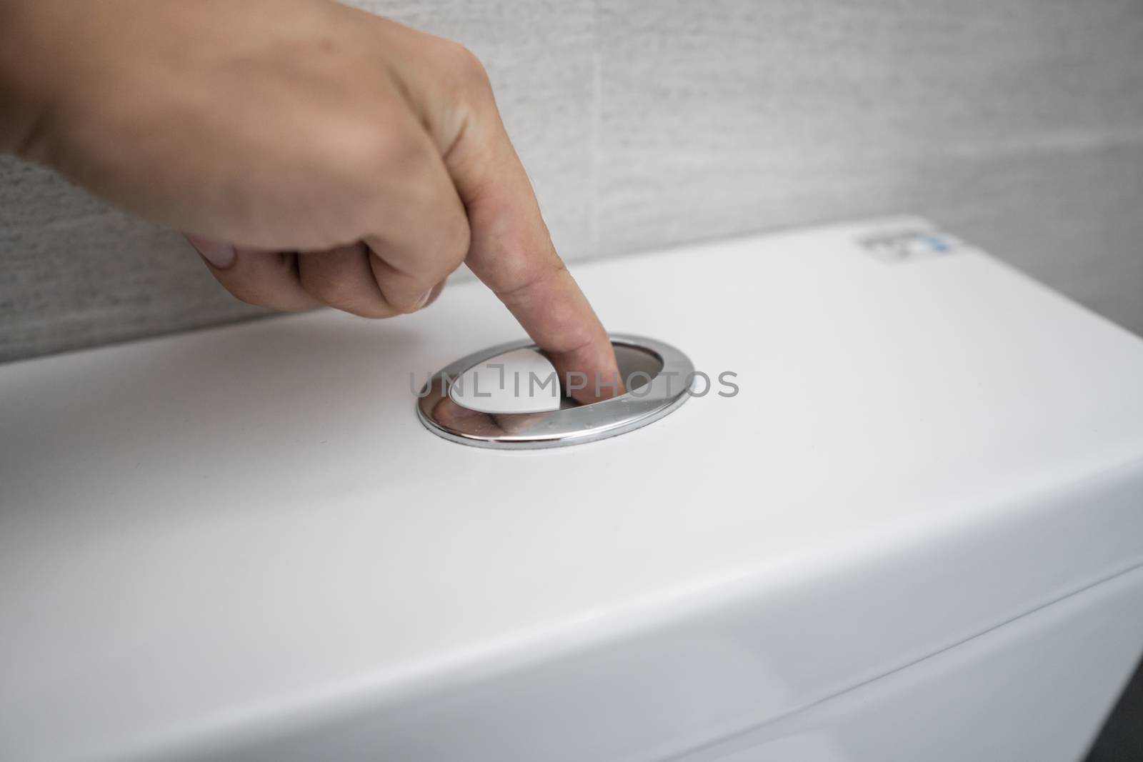 Close up of finger pushing a flush toilet button for cleaning a toilet