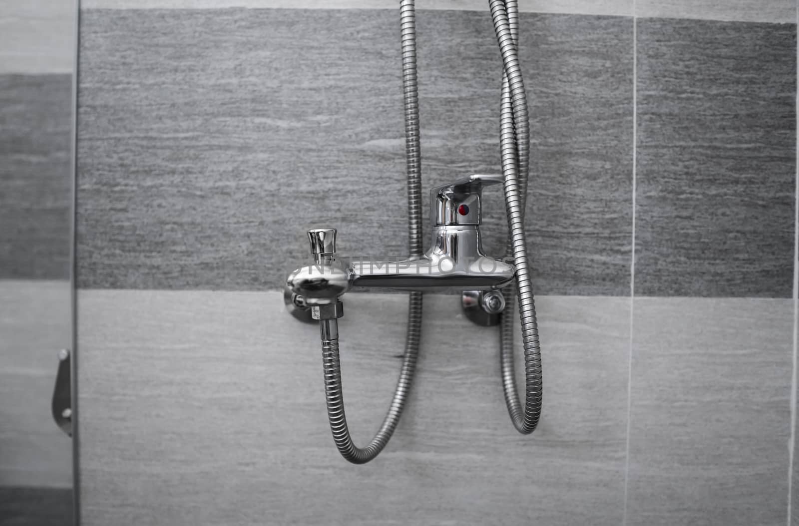 Modern designer tap and shower in bathroom. Closeup of chrome shower, faucet, in the bathroom covered decorative ceramic. Mixer cold hot water