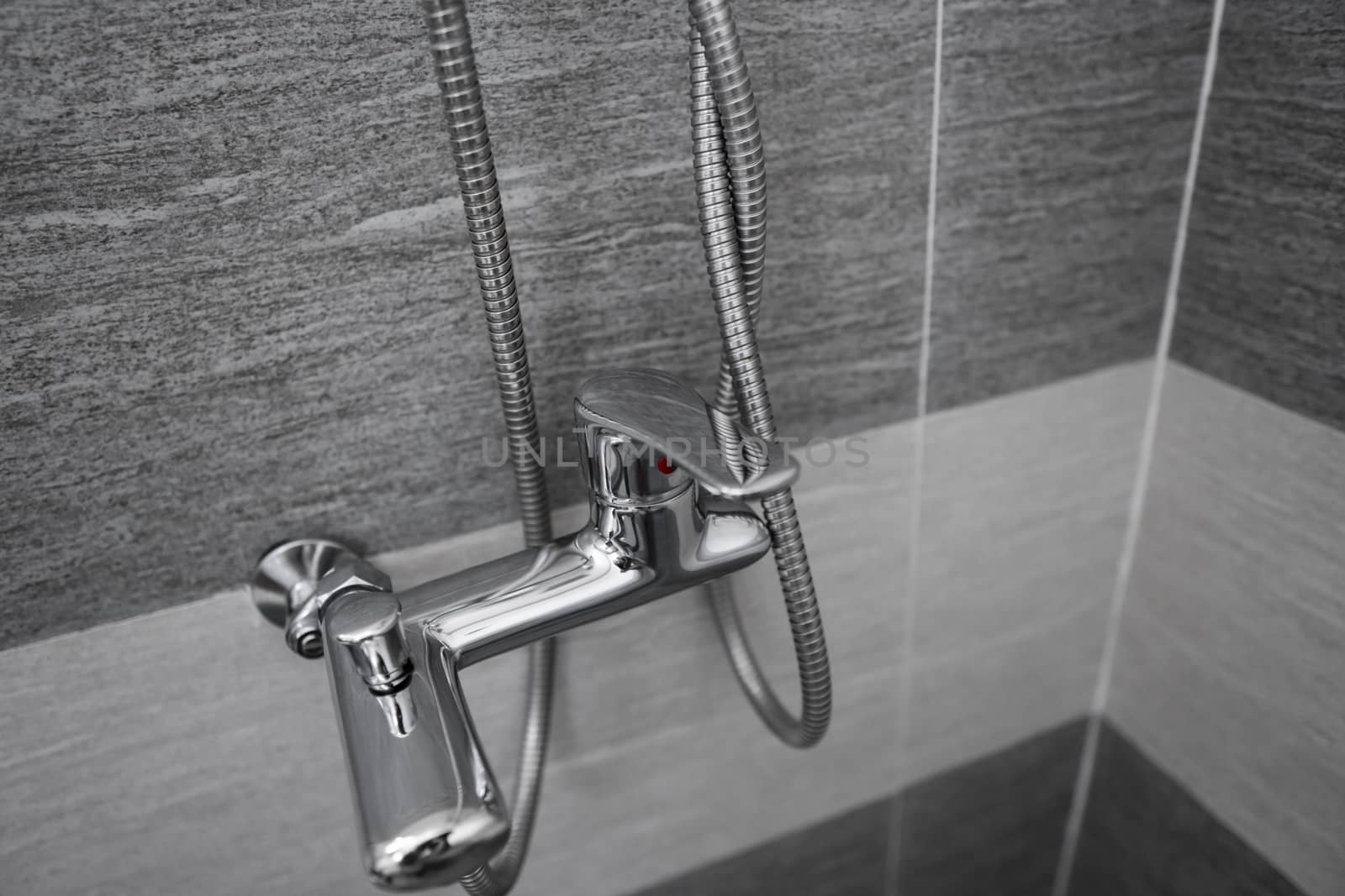 Modern designer tap and shower in bathroom. Closeup of chrome shower, faucet, in the bathroom covered decorative ceramic. Mixer cold hot water