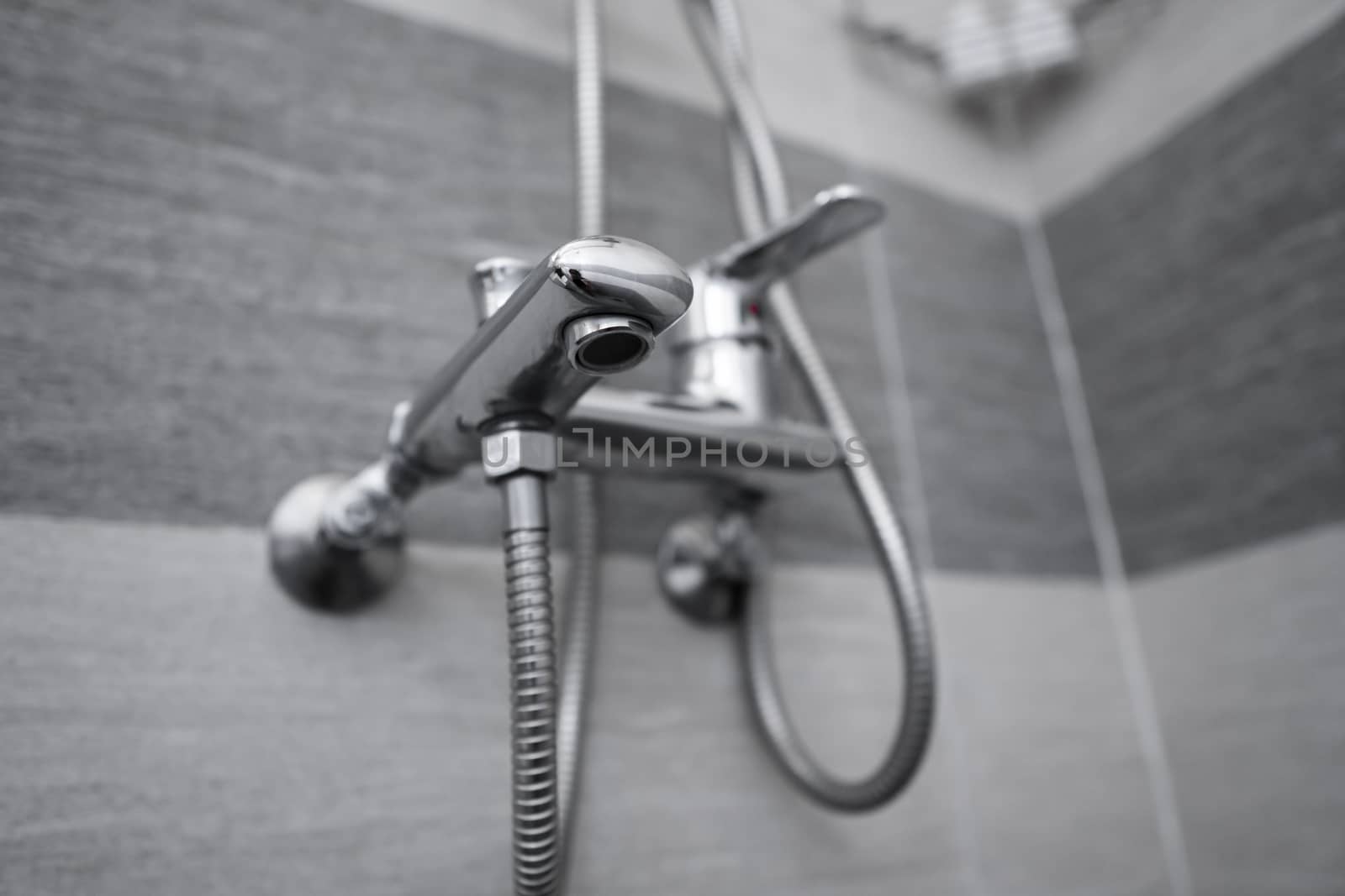 Modern designer tap and shower in bathroom. Closeup of chrome shower, faucet, in the bathroom covered decorative ceramic. Mixer cold hot water