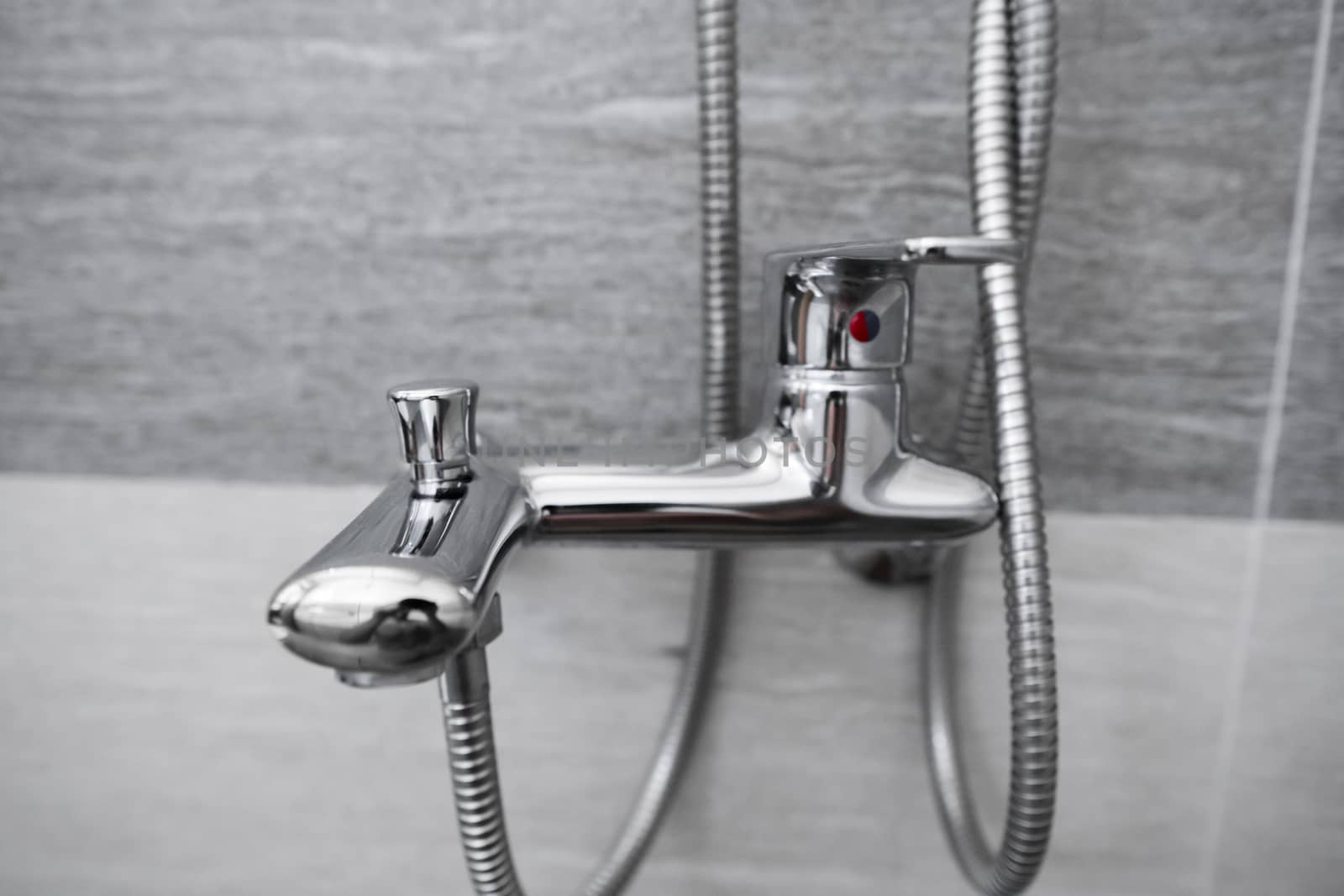 Modern designer tap and shower in bathroom. Closeup of chrome shower, faucet, in the bathroom covered decorative ceramic. Mixer cold hot water