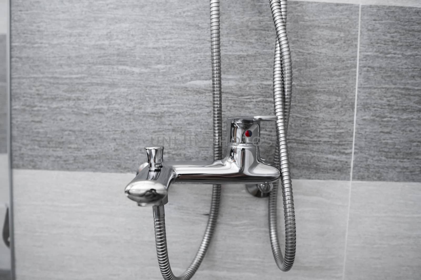 Modern designer tap and shower in bathroom. Closeup of chrome shower, faucet, in the bathroom covered decorative ceramic. Mixer cold hot water
