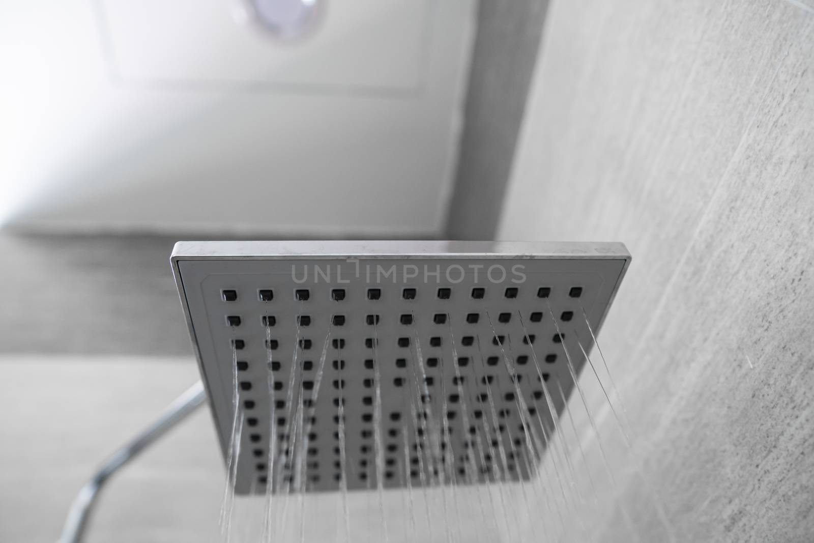 Water flowing from the square shower head in a modern bathroom. Shower in the bathroom with water spray or water. A stream of fresh water from the shower head to clean the dirty body