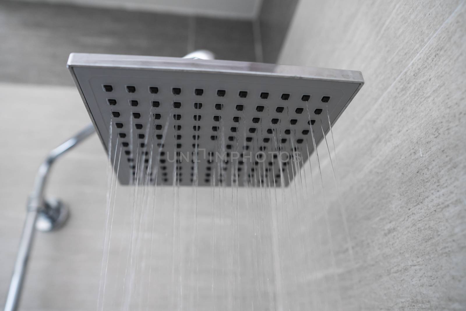 Water flowing from the square shower head in a modern bathroom. Shower in the bathroom with water spray or water. A stream of fresh water from the shower head to clean the dirty body