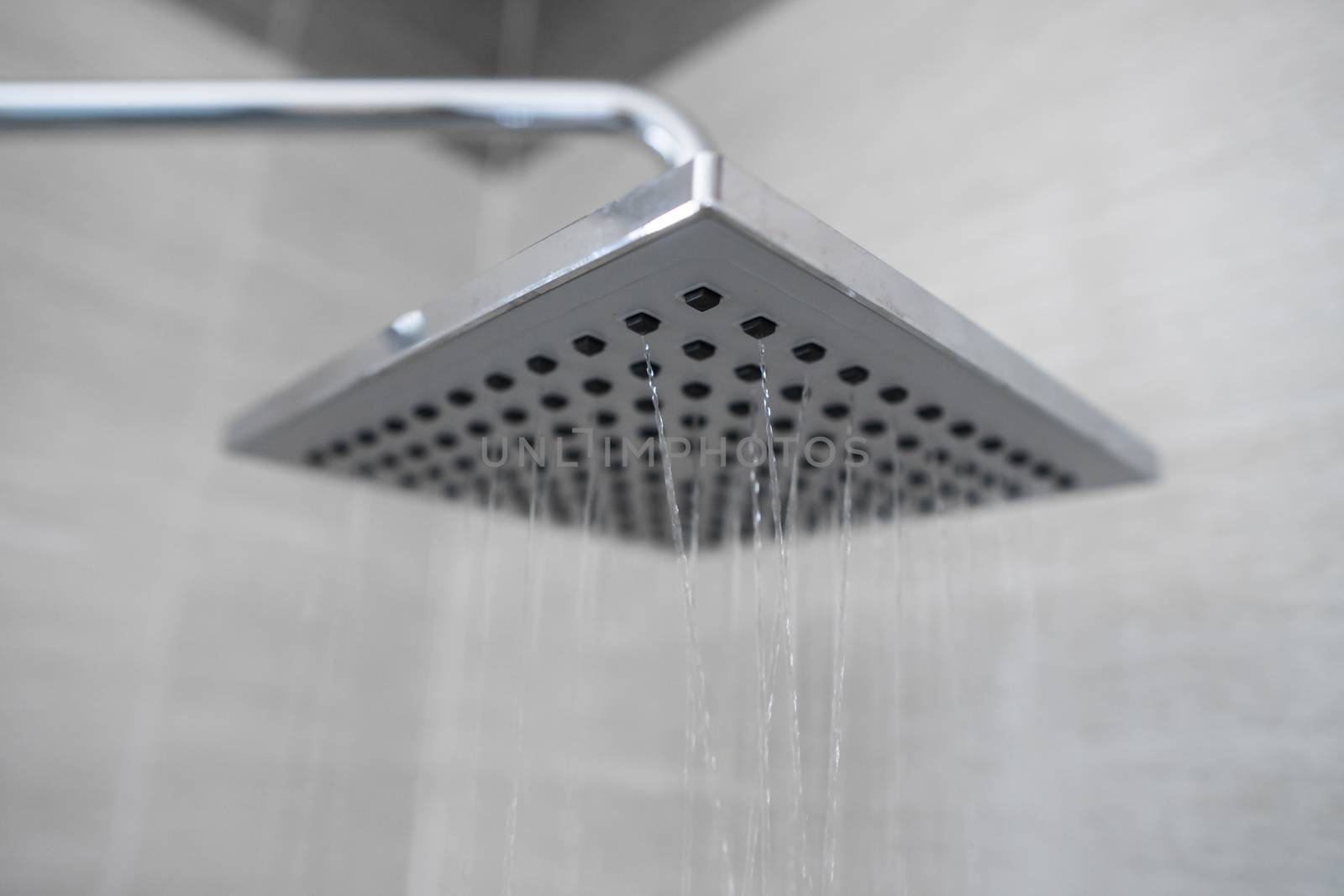 Water flowing from the square shower head in a modern bathroom. Shower in the bathroom with water spray or water. A stream of fresh water from the shower head to clean the dirty body