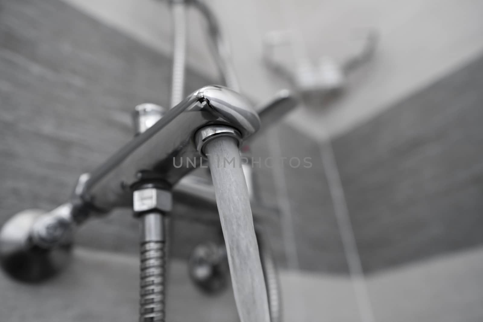 Water flows from the mixer. Modern designer tap and shower in bathroom. Closeup of chrome shower, faucet, in the bathroom covered decorative ceramic. Mixer cold hot water