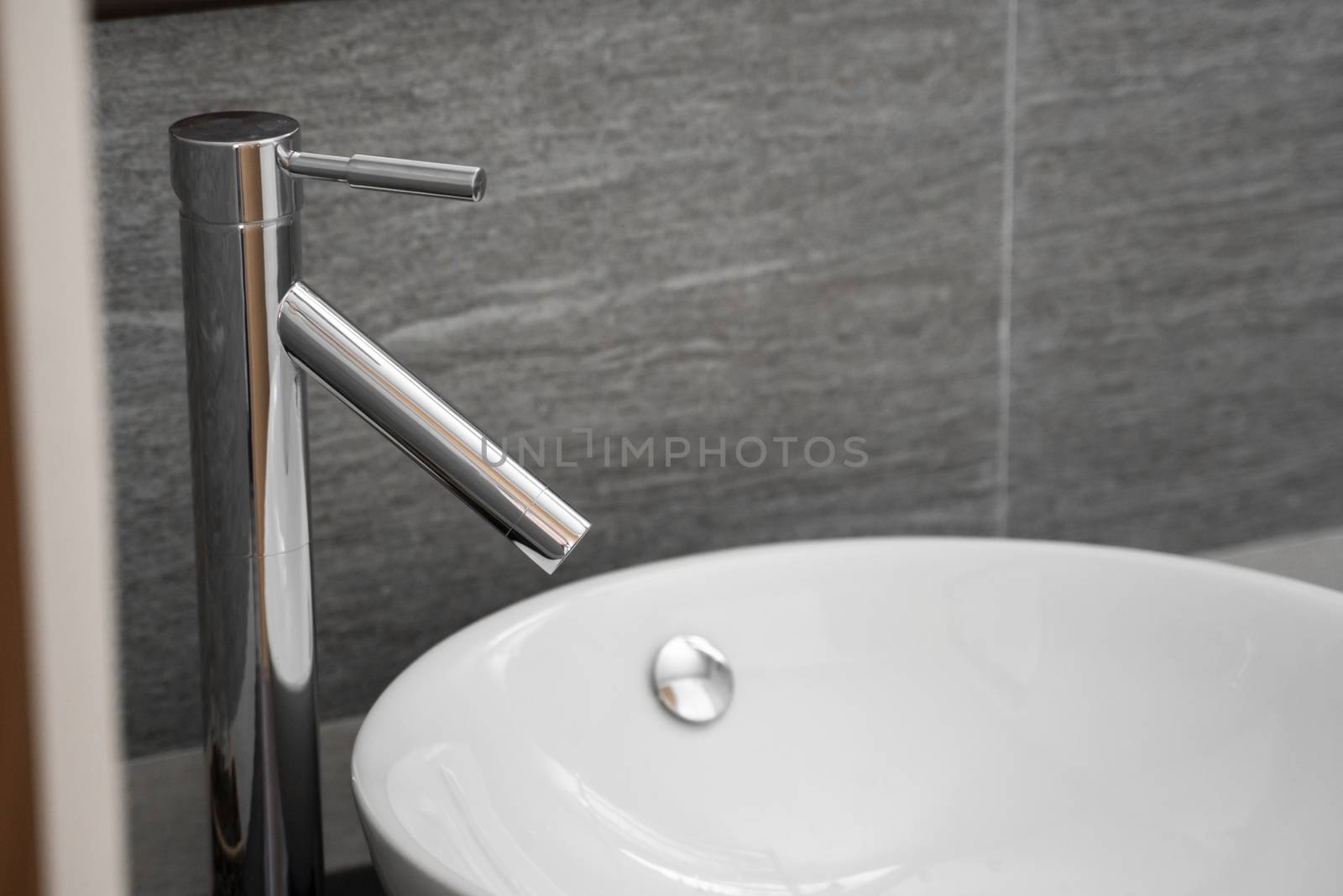 Bathroom interior with white round sink and chrome faucet in a modern bathroom