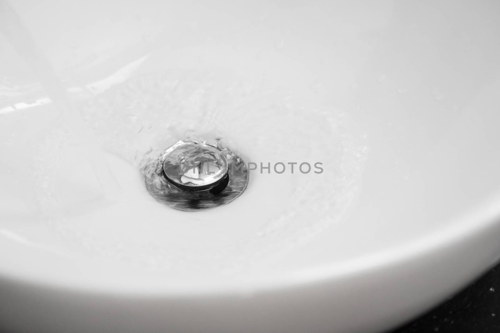 Bathroom interior with white round sink and chrome faucet in a modern bathroom. Water flowing from the chrome faucet. by vovsht