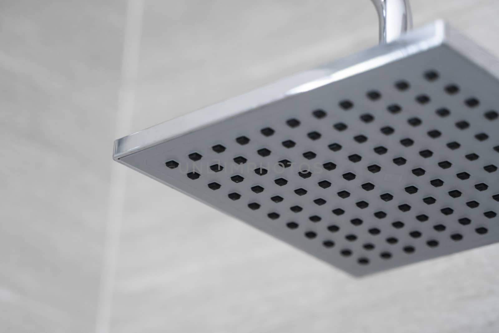 Square shower head in a modern bathroom. Shower in the bathroom with water spray or water. Feel relaxed and enjoy in the bathroom. A stream of fresh water from the shower head to clean the dirty body. by vovsht