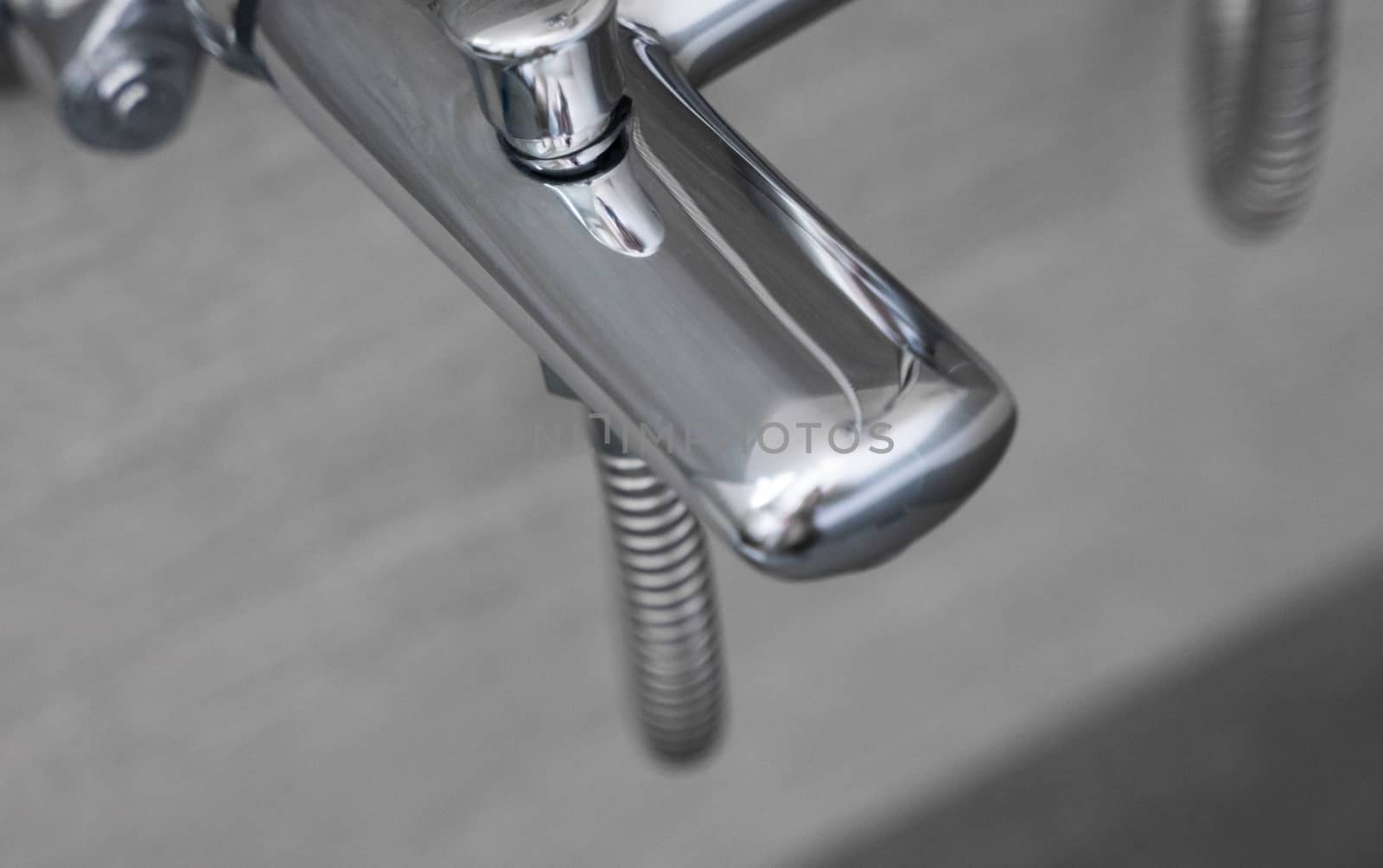 Modern designer tap and shower in bathroom. Closeup of chrome shower, faucet, in the bathroom covered decorative ceramic. Mixer cold hot water