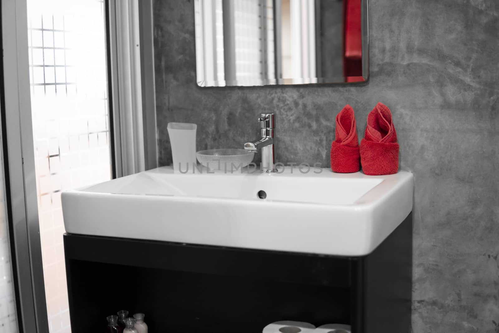 Modern stainless steel faucet with wash basin sink with a two red towels on it . Counter bathroom interior contemporary. Luxury and stylish design bathroom with a concrete style walls