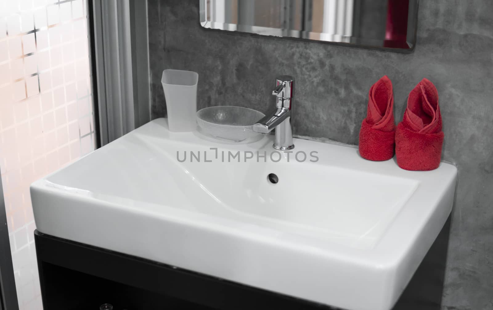 Modern stainless steel faucet with wash basin sink with a two red towels on it . Counter bathroom interior contemporary. Luxury and stylish design bathroom with a concrete style walls