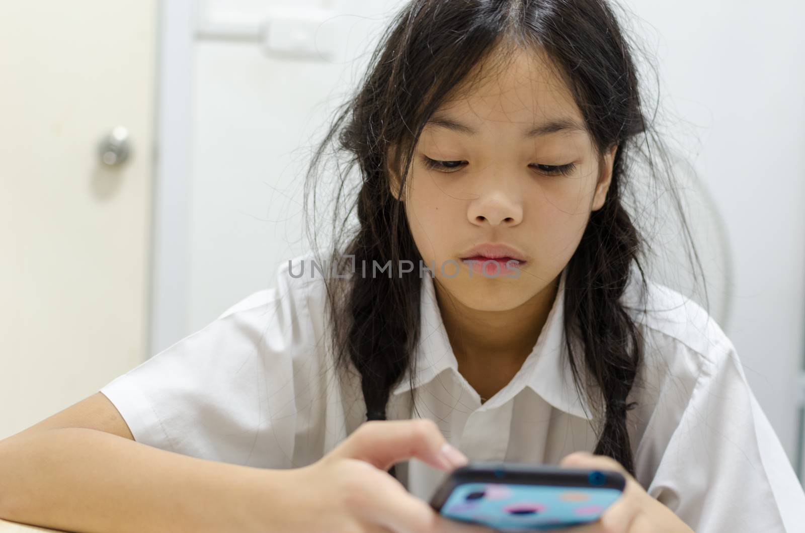 Young schoolgirl addicted to mobile phone games. Makes him not interested in doing homework.