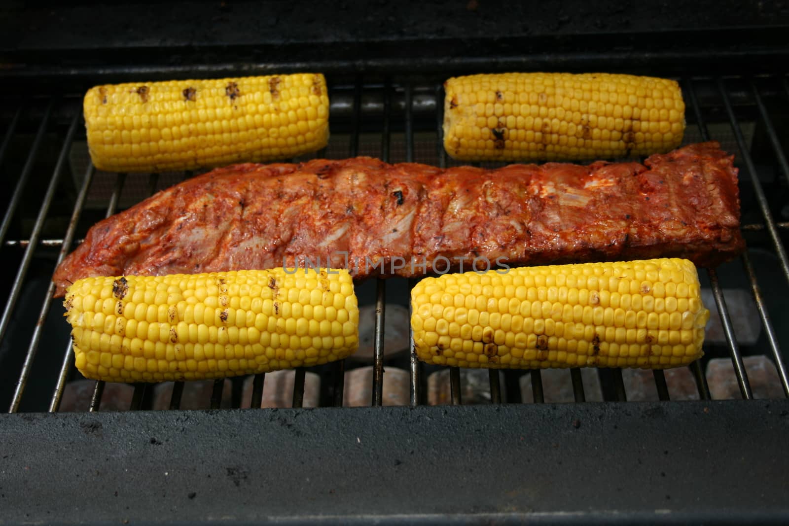 A large piece of meat and may four-piston on a gas Grill