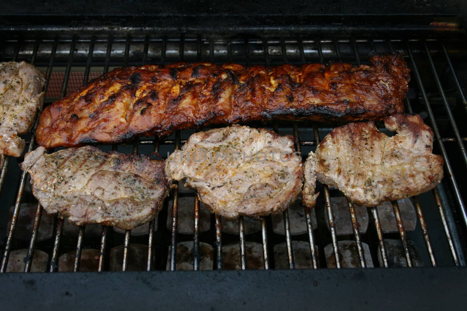 A large piece of meat and four small on a gas Grill 
