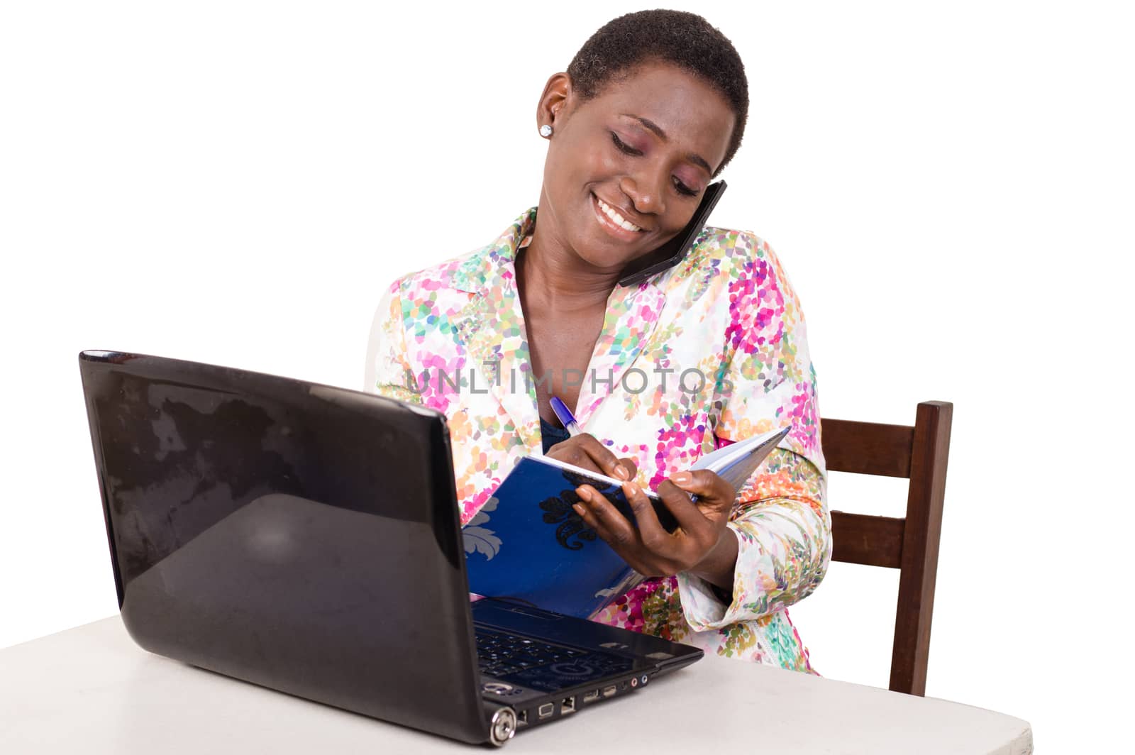 Young businesswoman sitting at the desk, her laptop in front of her communicating taking notes