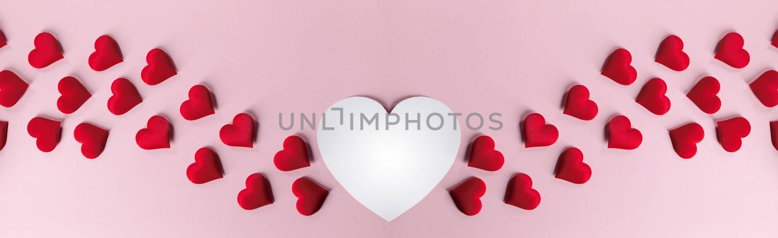 Valentine's day many red silk hearts and white heart shape card on pink paper background , border frame on red with copy space, love concept