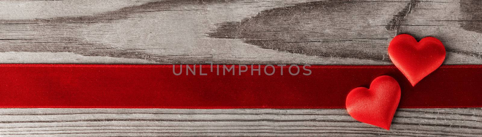 Valentine's day two red silk hearts and ribbon stripe on wooden background, love concept