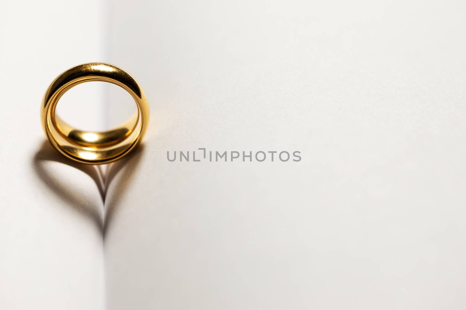 Two golden wedding rings on blank book pages background with copy space for text