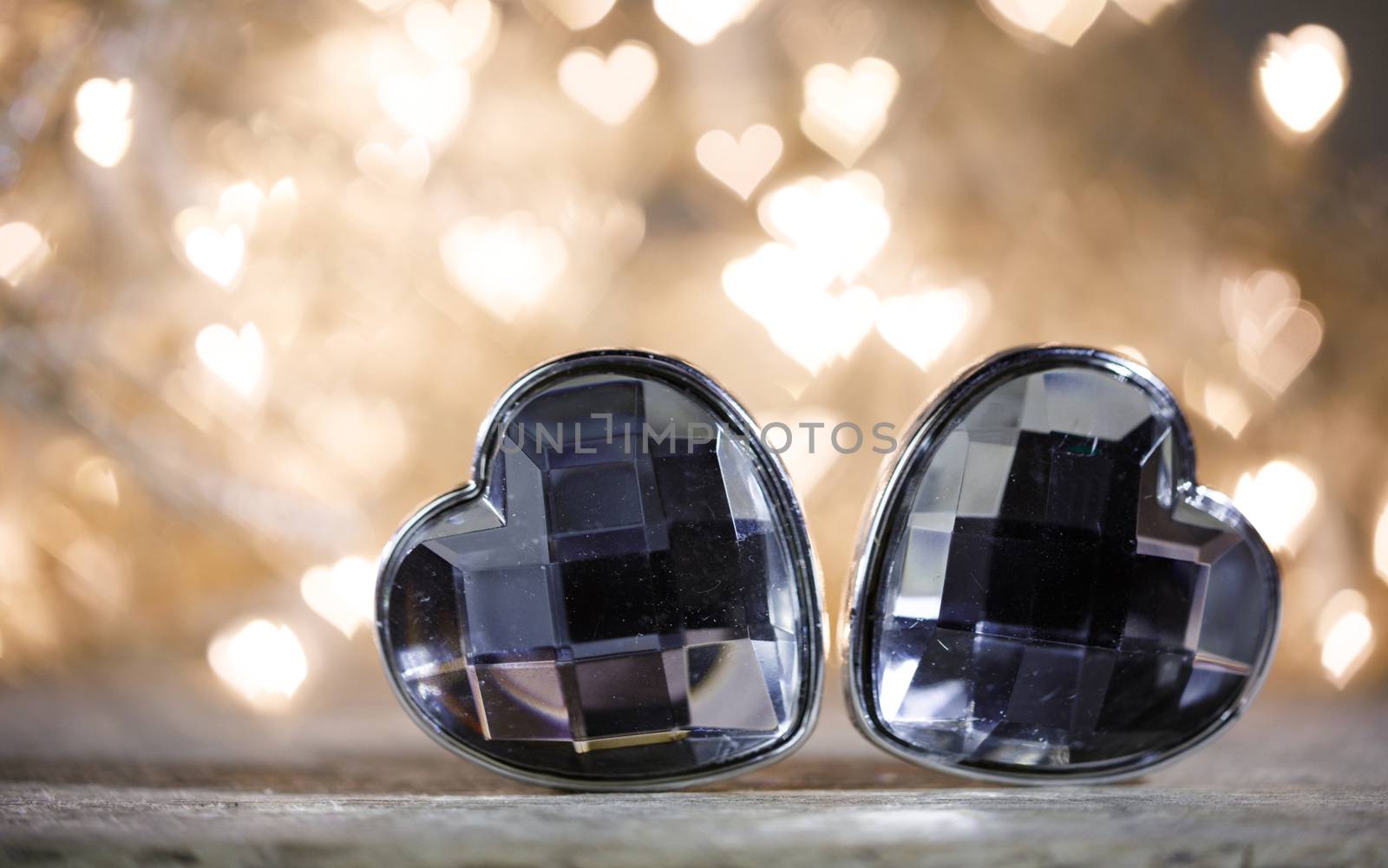 Two jewel hearts on golden shiny light garland background