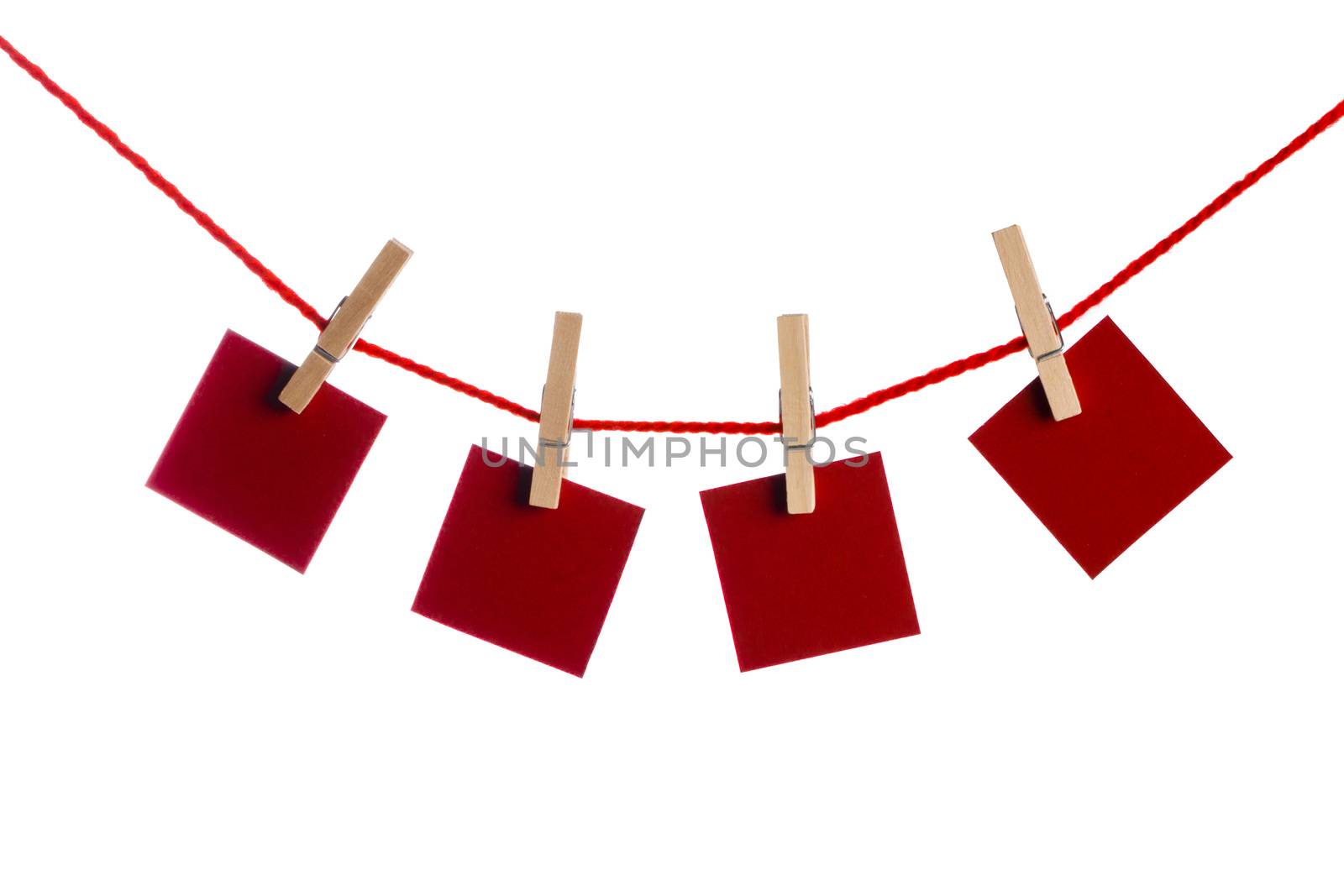 Set of four red blank paper notes held on a string with clothespins isolated on white background