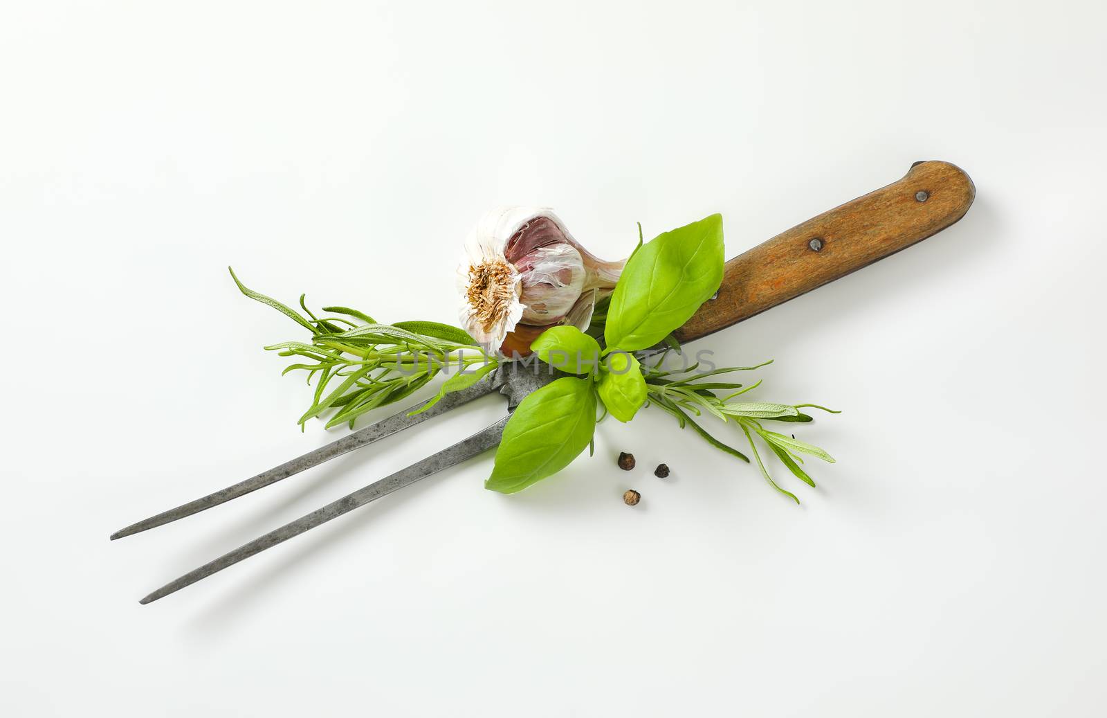 Old carving / meat fork, fresh culinary herbs, garlic and three peppercorns