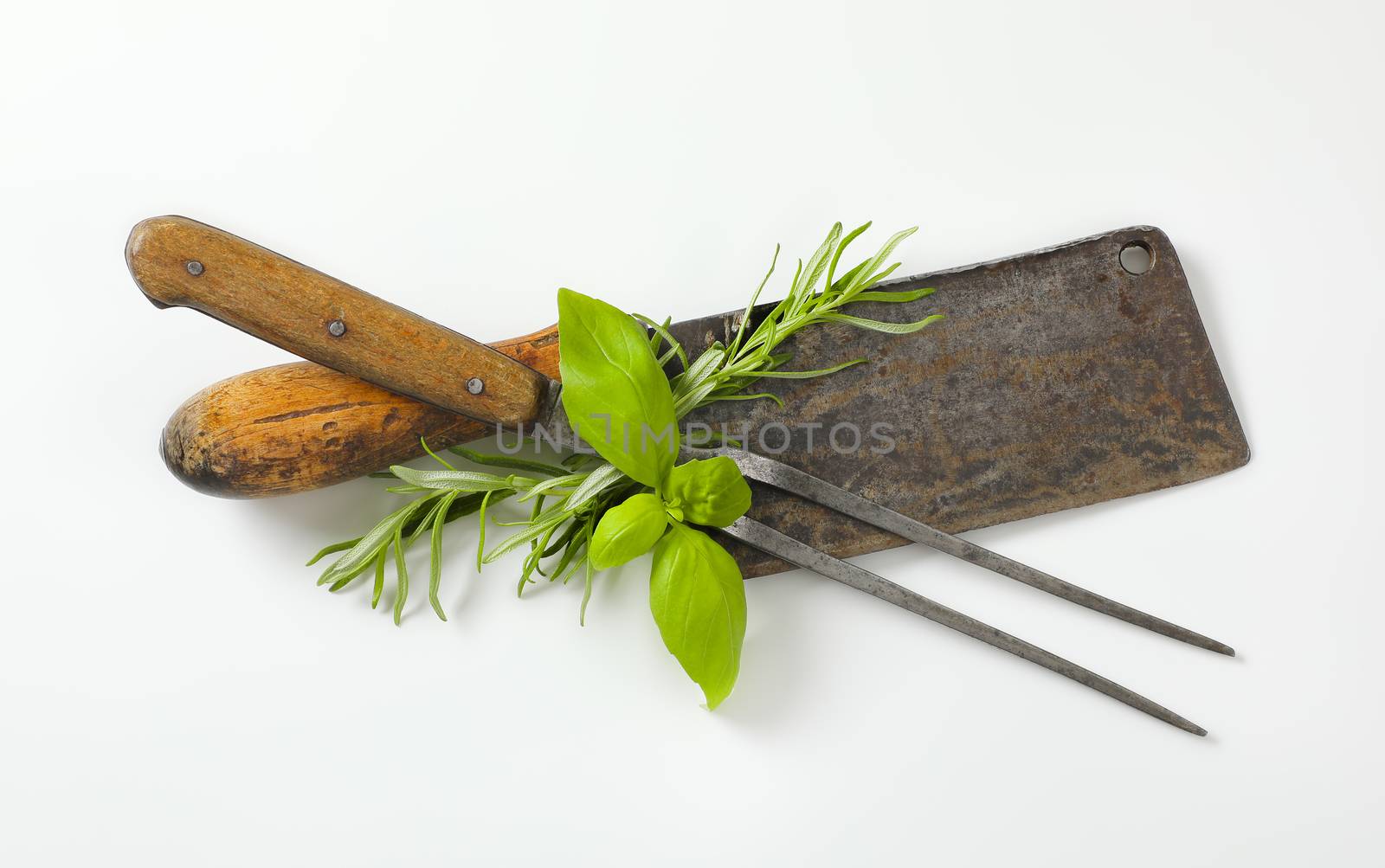 Old meat cleaver knife, carving fork and fresh culinary herbs