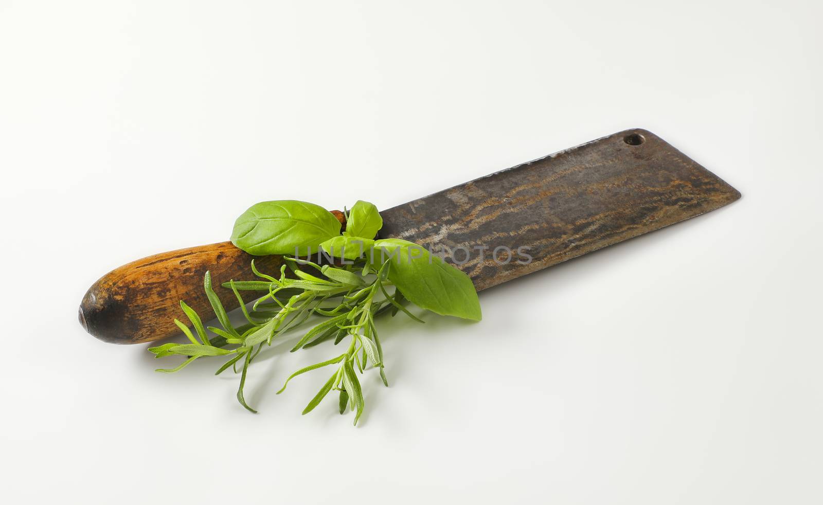 Old rusty meat cleaver knife with fresh basil and rosemary