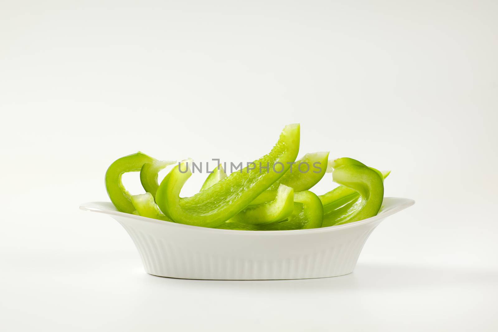 Slices of fresh green bell pepper in white bowl