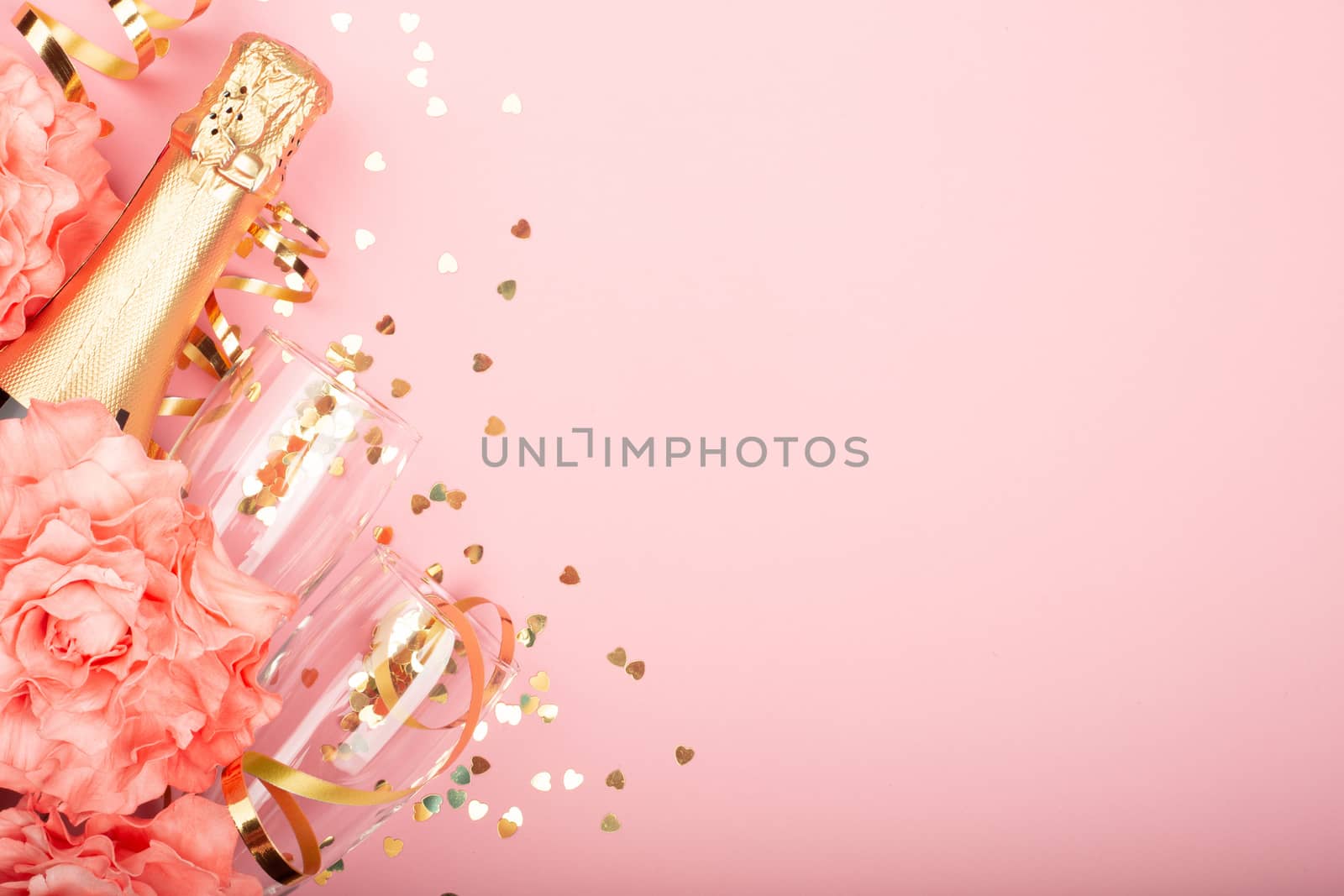 Valentines day champagne bottle flute glasses golden confetti hearts rose flowers and serpentine on pink background with copy space for text