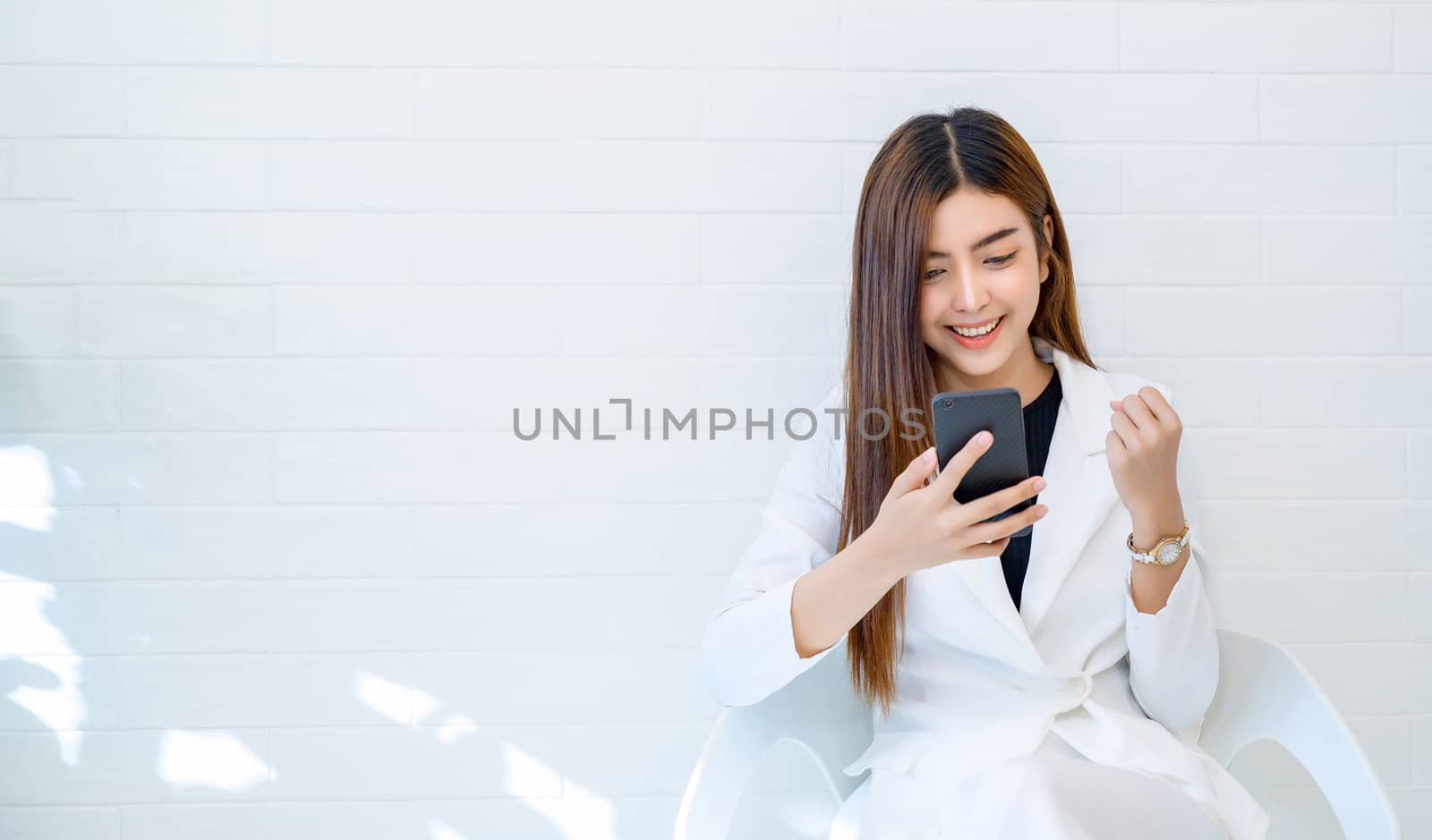 Business women wear white clothes glad to play mobile phone in a white background