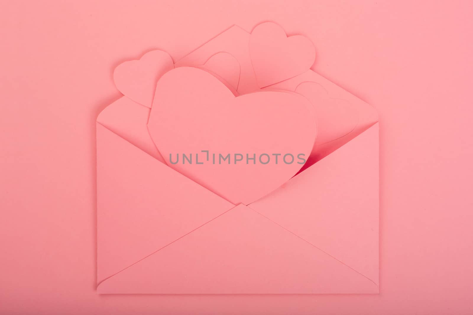 Pink love letter and paper hearts on pink background with copy space for text