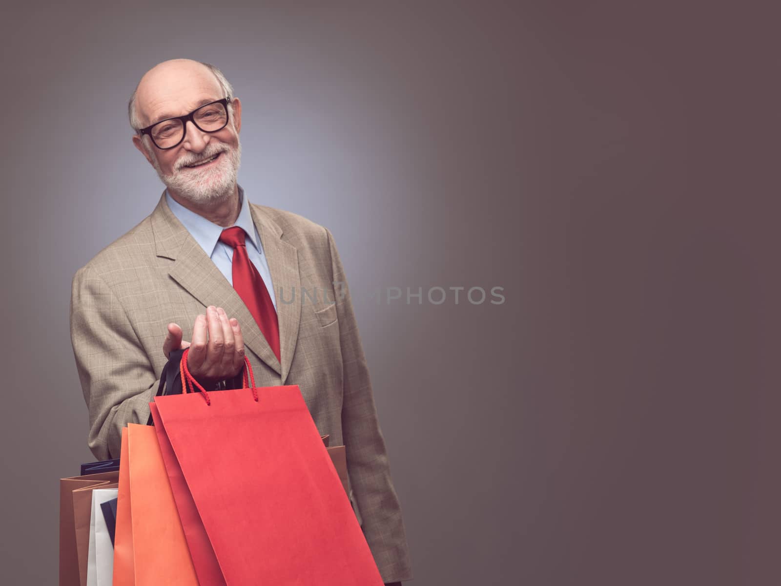 Shopper senior man holding shopping bags standing happy smiling and excited , background with copy space