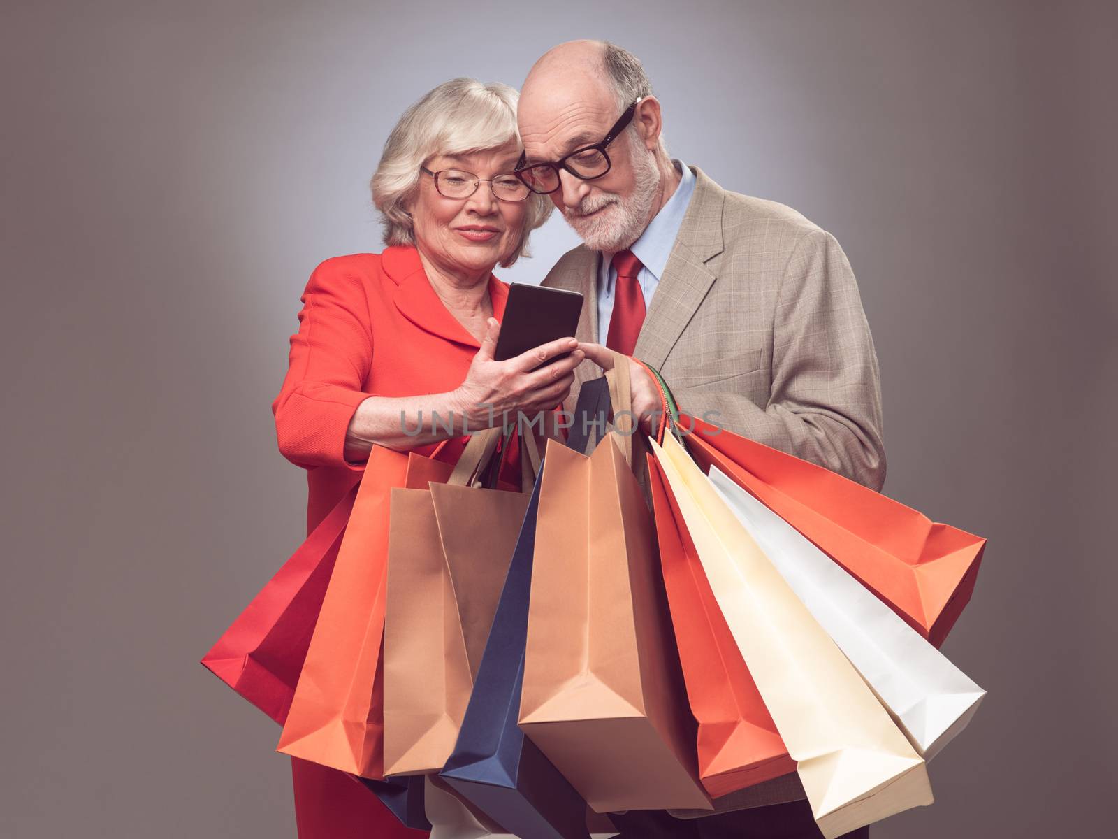 Happy elder couple with many shopping bags surfing the net online shopping concept