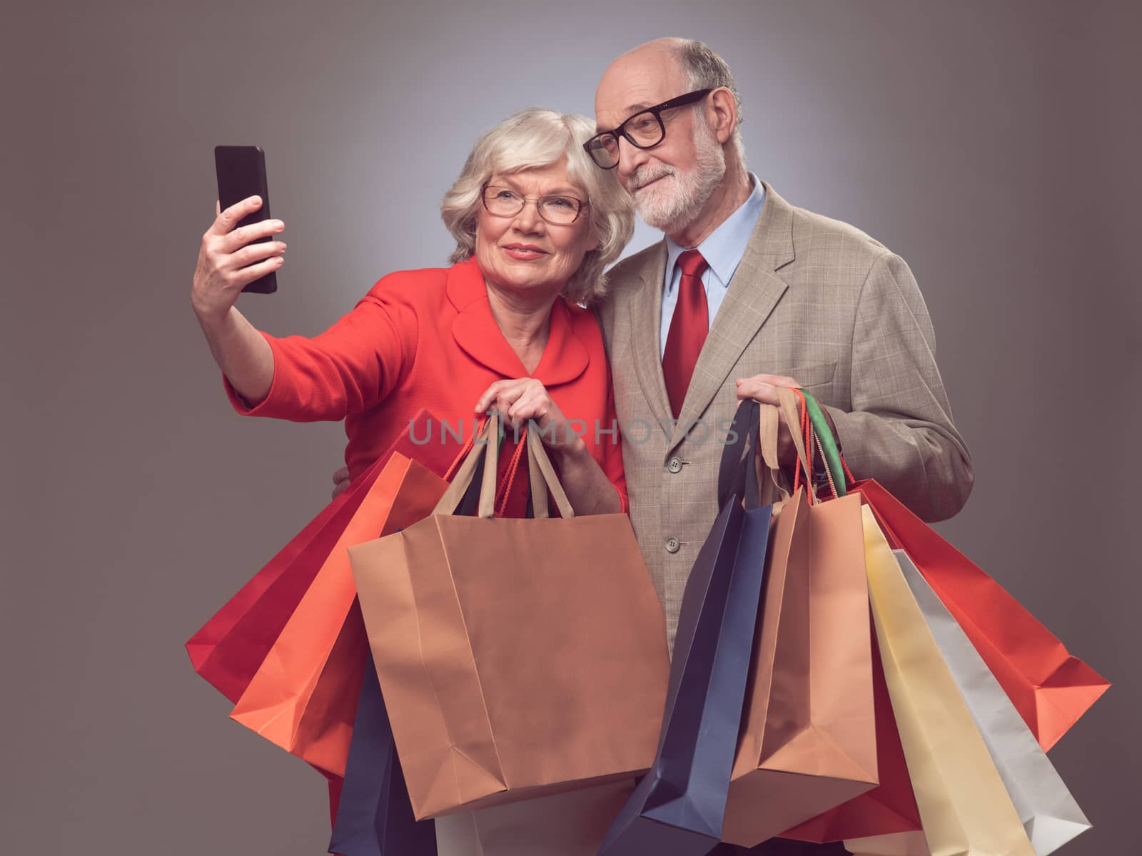 Senior couple with many paper shopping bags taking selfie